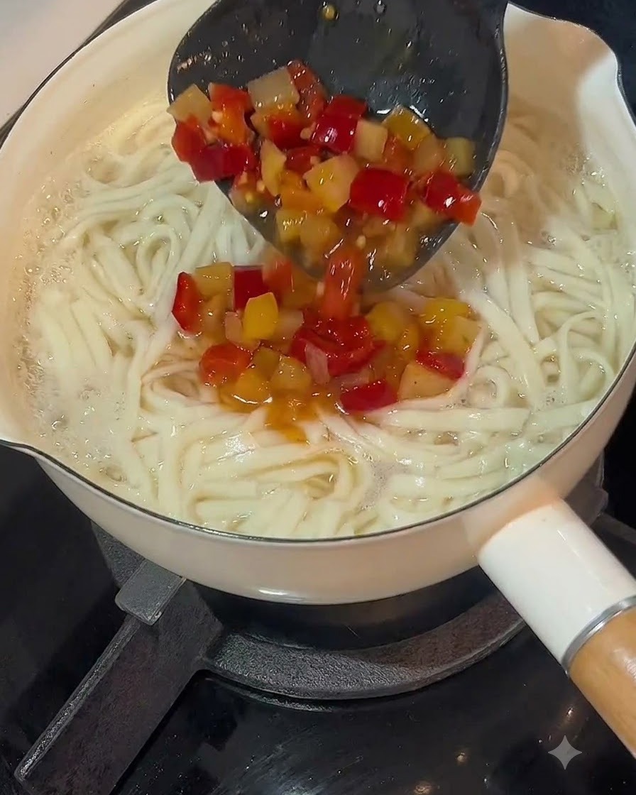 Un mestolo che versa la base di zuppa al peperoncino e sottaceto sopra una pentola di noodle cotti.