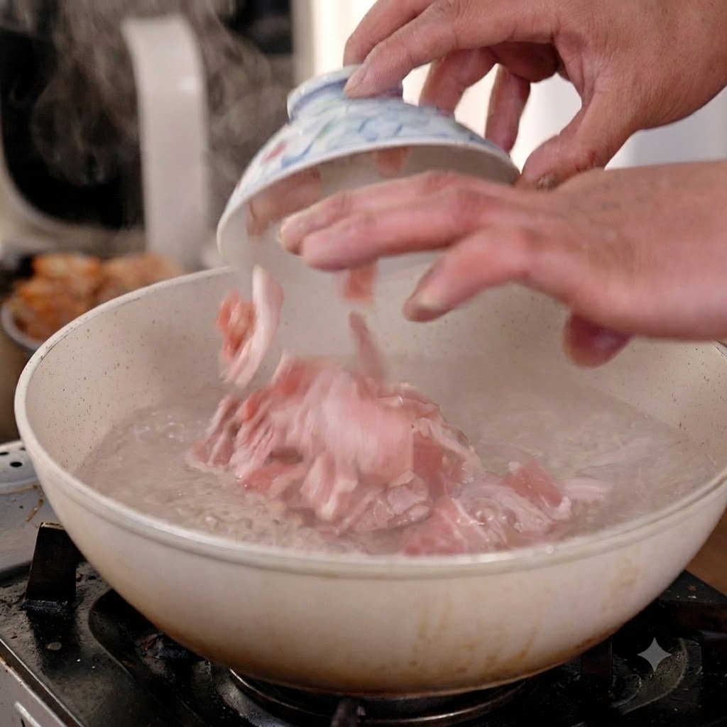 Mani che fanno cadere fette di pancetta di maiale cruda da una piccola ciotola di ceramica in una padella di acqua bollente.