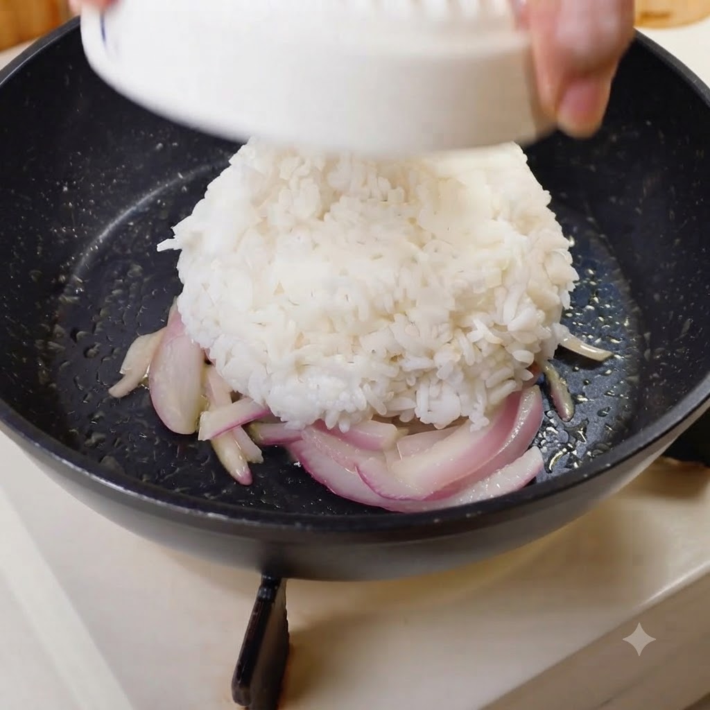 Una cupola modellata di riso bianco che viene capovolta al centro di una padella con le cipolle.