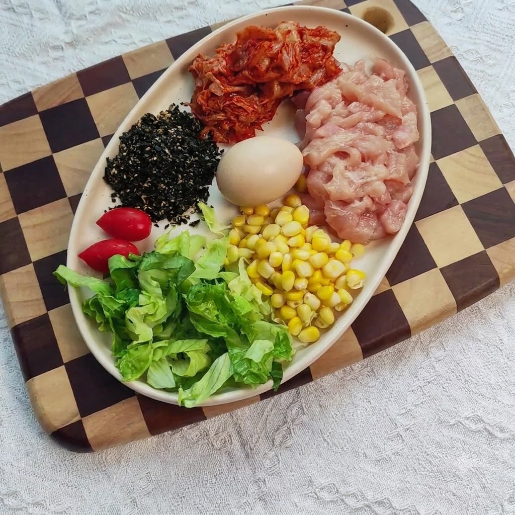 Petto di pollo a dadi in una ciotola mescolato con condimenti, zenzero e aglio.