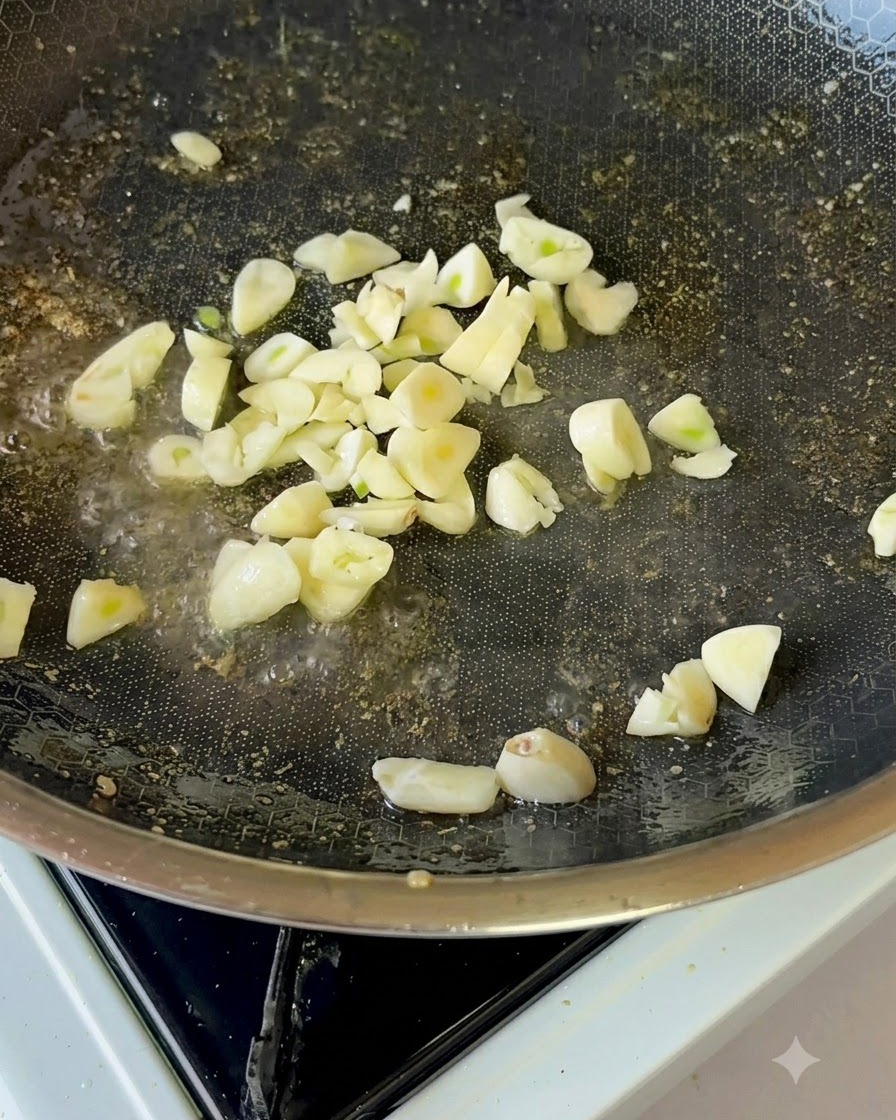 Fette di aglio fresco che friggono delicatamente nellolio da cucina allinterno di una padella antiaderente.