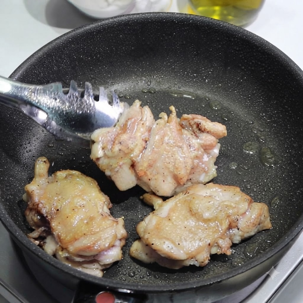 Pinze che rimuovono le cosce di pollo dorate da una padella su un tagliere per essere affettate.