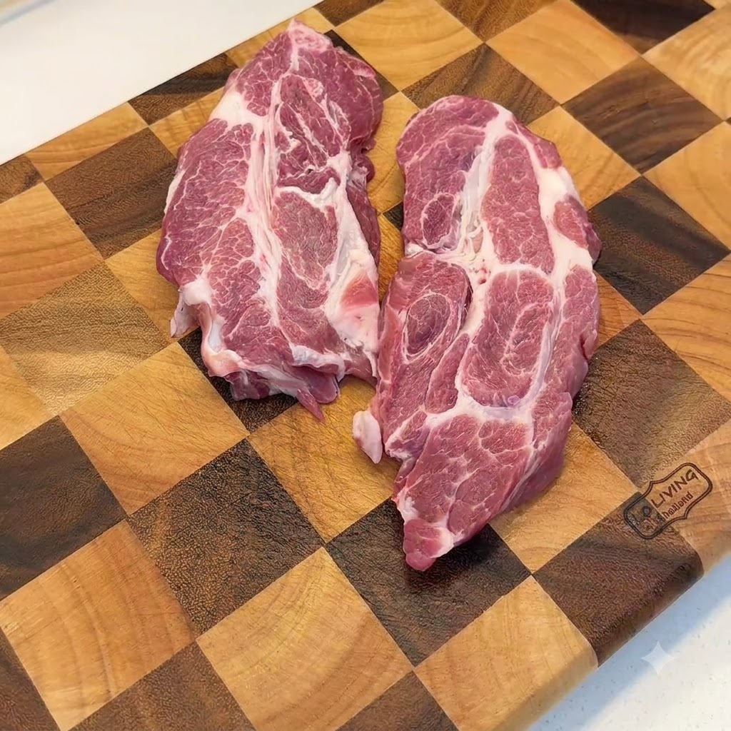 Tagli di spalla di maiale cruda battuti con un batticarne in metallo su un tagliere di legno.