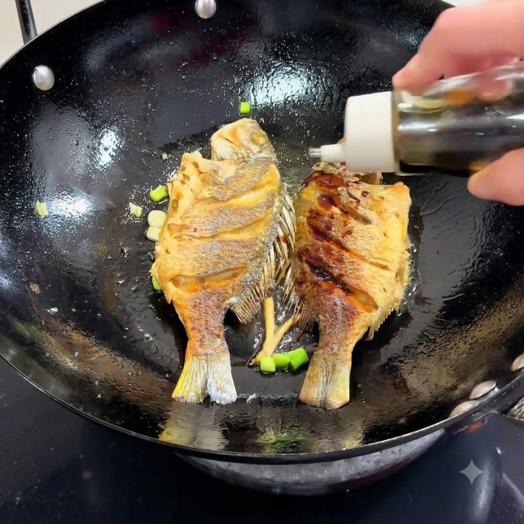 Salsa di soia versata da una bottiglia in un wok contenente il pesce e i cipollotti fritto in padella.