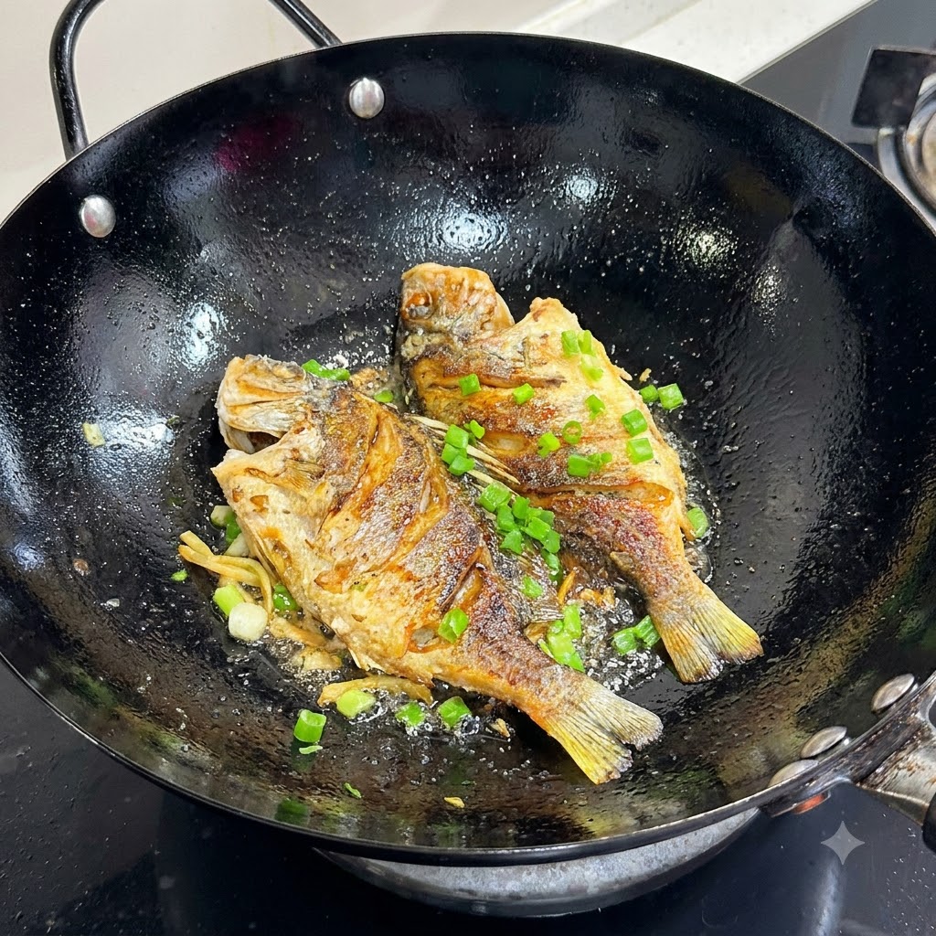 Cipollotti freschi tritati cosparsi sopra il pesce dorato in un wok nero.