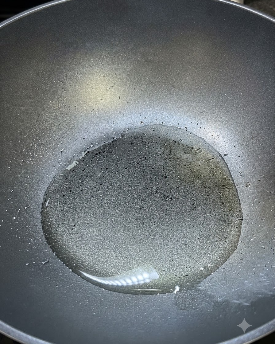 Olio da cucina caldo che luccica allinterno di un wok scuro pronto per essere insaporito.
