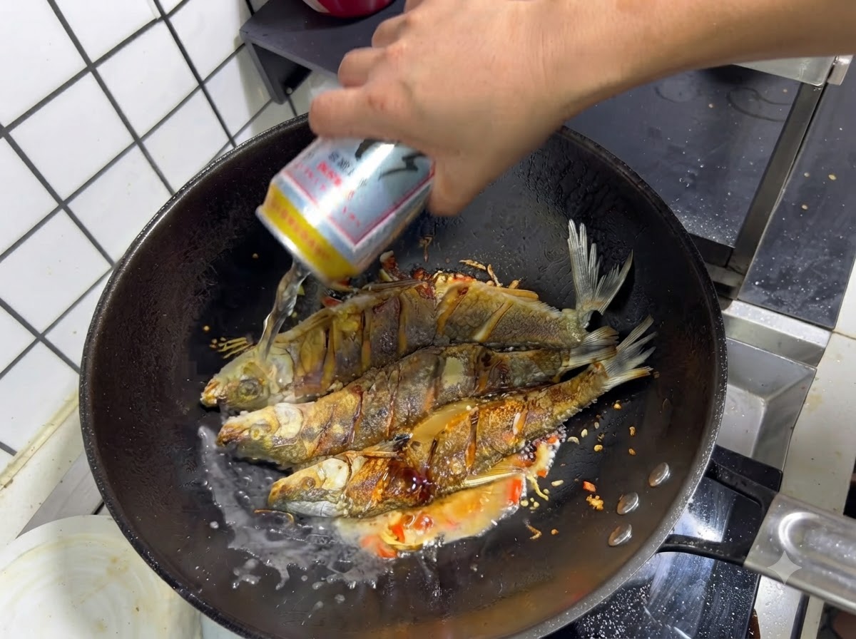 Una mano che versa una lattina di birra in un wok sopra il pesce fritto condito e gli aromi saltati.