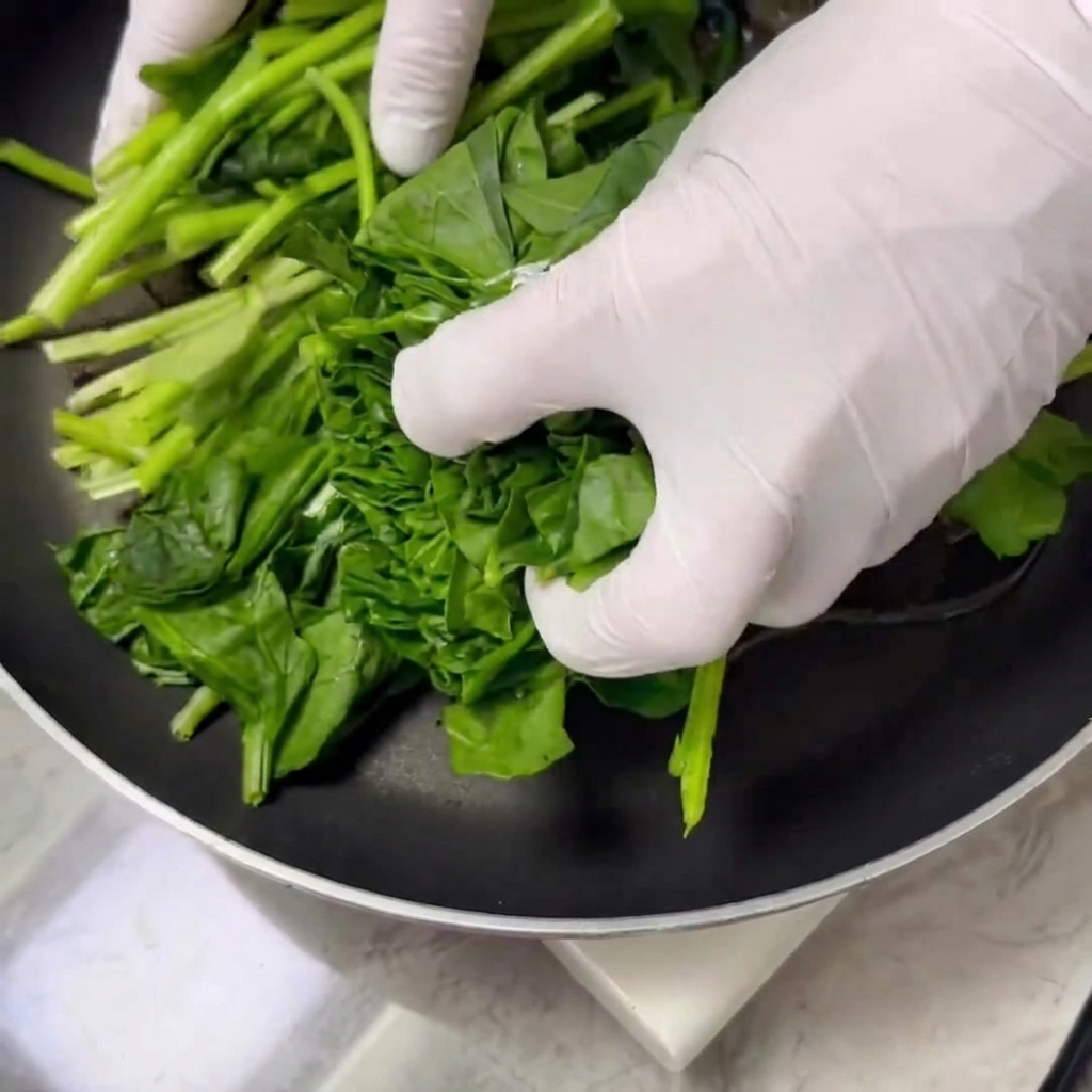 Foglie di spinaci fresche saltate e cotte in padella con olio e sale.