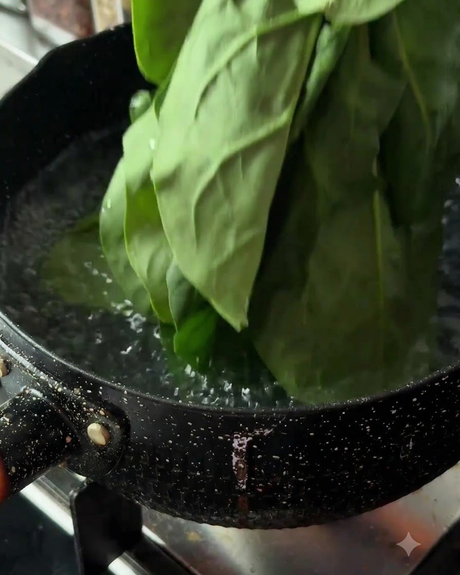 Foglie di spinaci freschi immerse in una pentola di acqua bollente su un fornello.