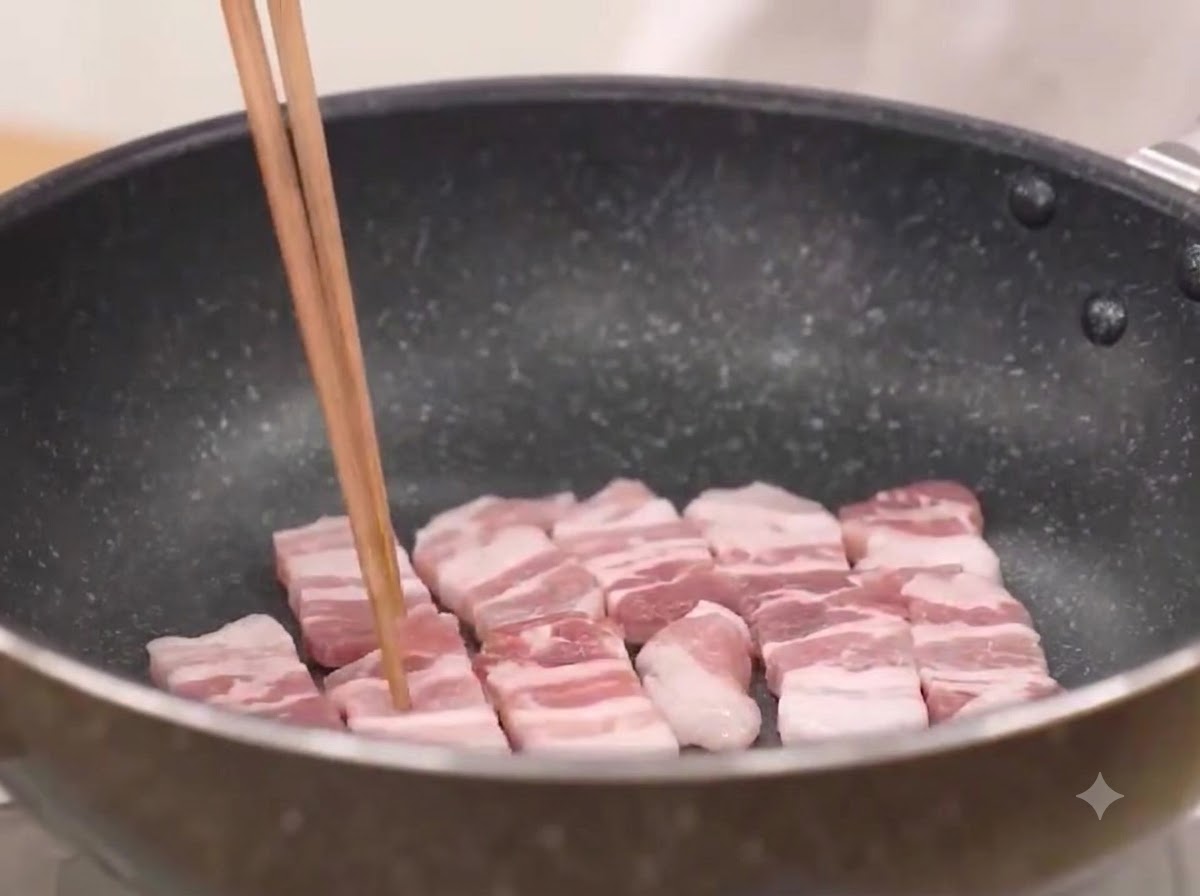 Fette di pancetta di maiale fritte in una padella calda fino a doratura sfrigolante.