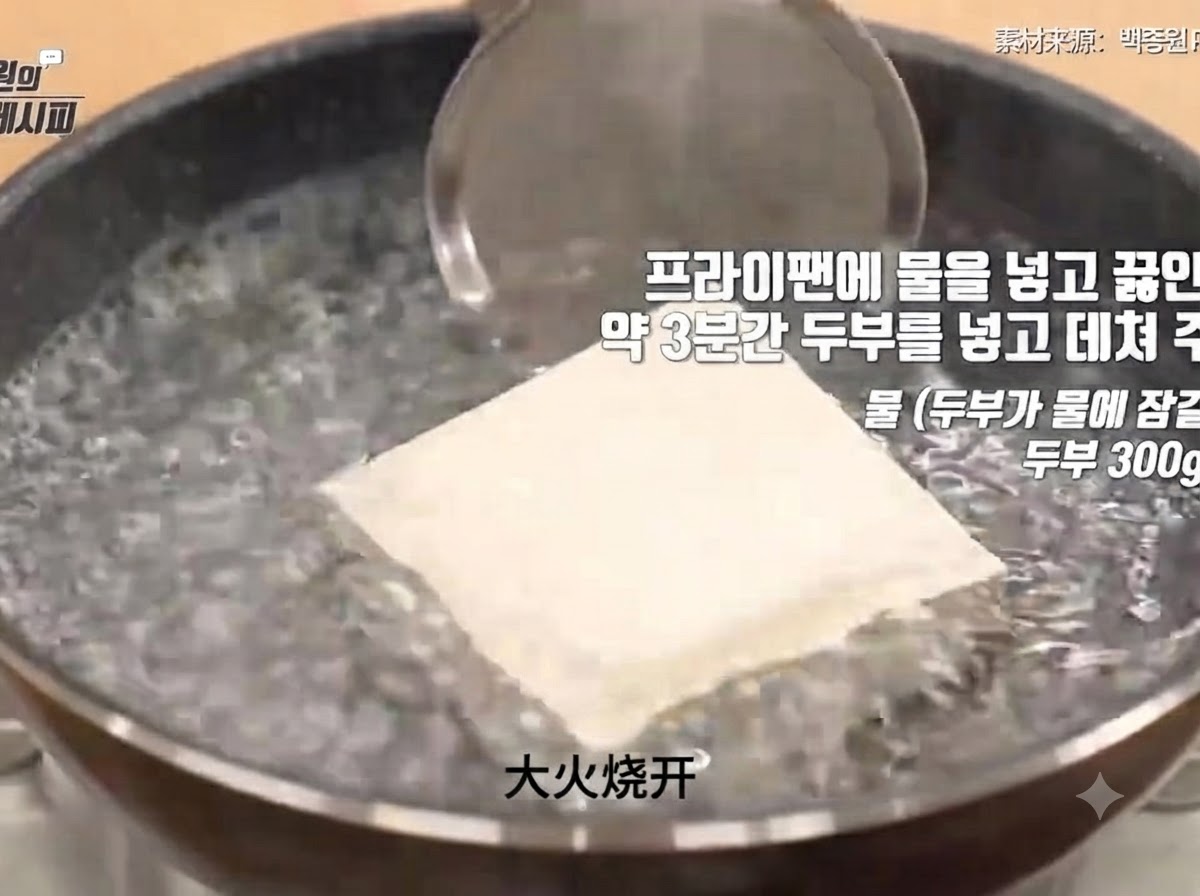 Un blocco di tofu fermo immerso in una pentola di acqua bollente vigorosamente durante il processo di sbollentatura.