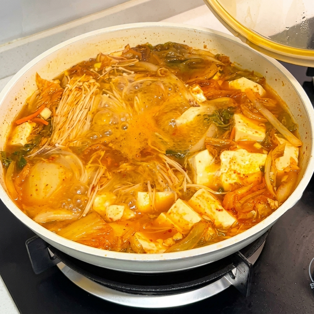 Un cucchiaio di salsa di pasta di peperoncino coreana versato in una pentola di zuppa che bolle.