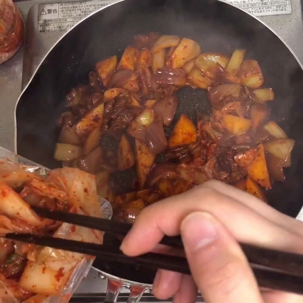Kimchi aggiunto nella padella e mescolato con gli altri ingredienti.