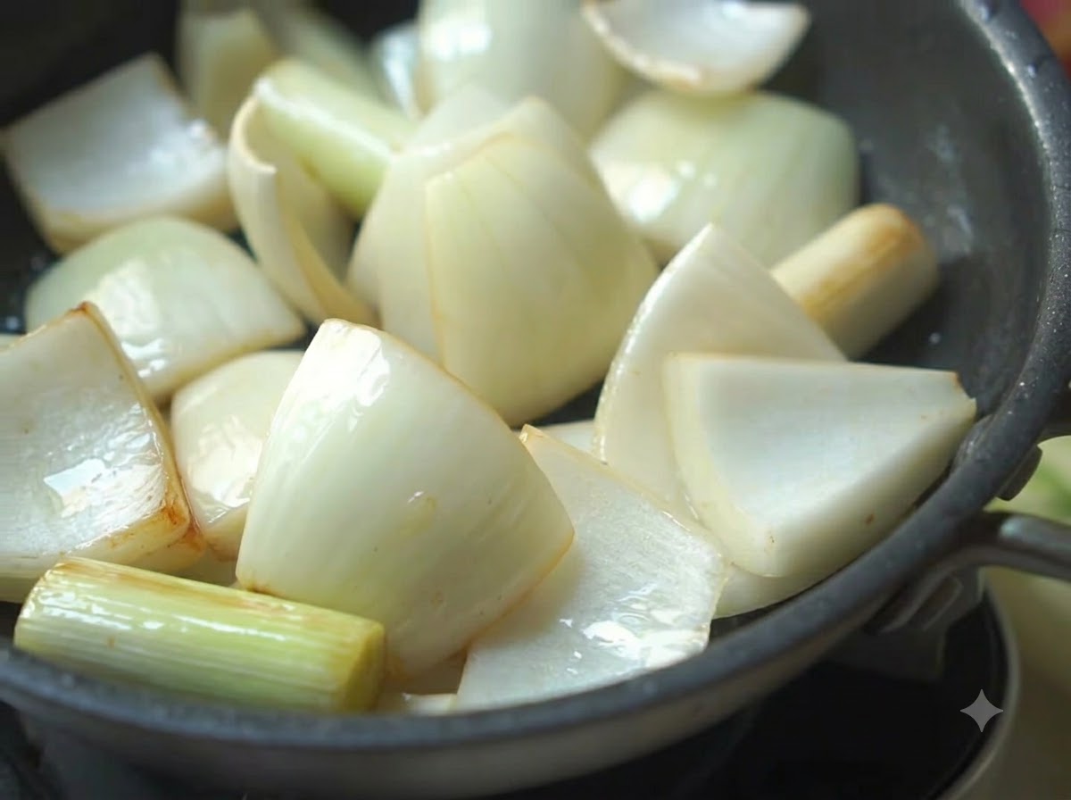 Cipolle, cipollotti e peperoni verdi che sfrigolano in una padella con olio.
