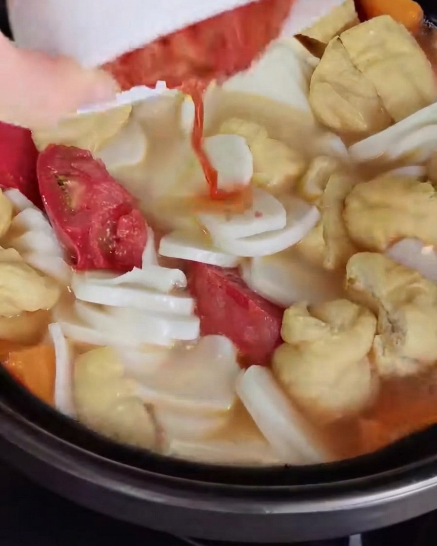 Kimchi tritato versato e mescolato nel brodo della zuppa.