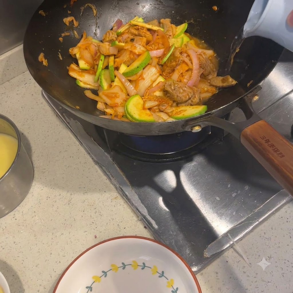 Acqua calda versata da un bollitore chiaro in un wok pieno di ingredienti saltati.