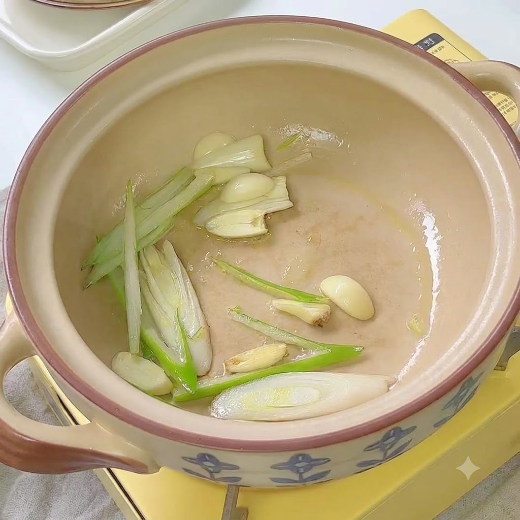 Kimchi saltato in padella con cipollotti e aglio allinterno della pentola di ceramica.