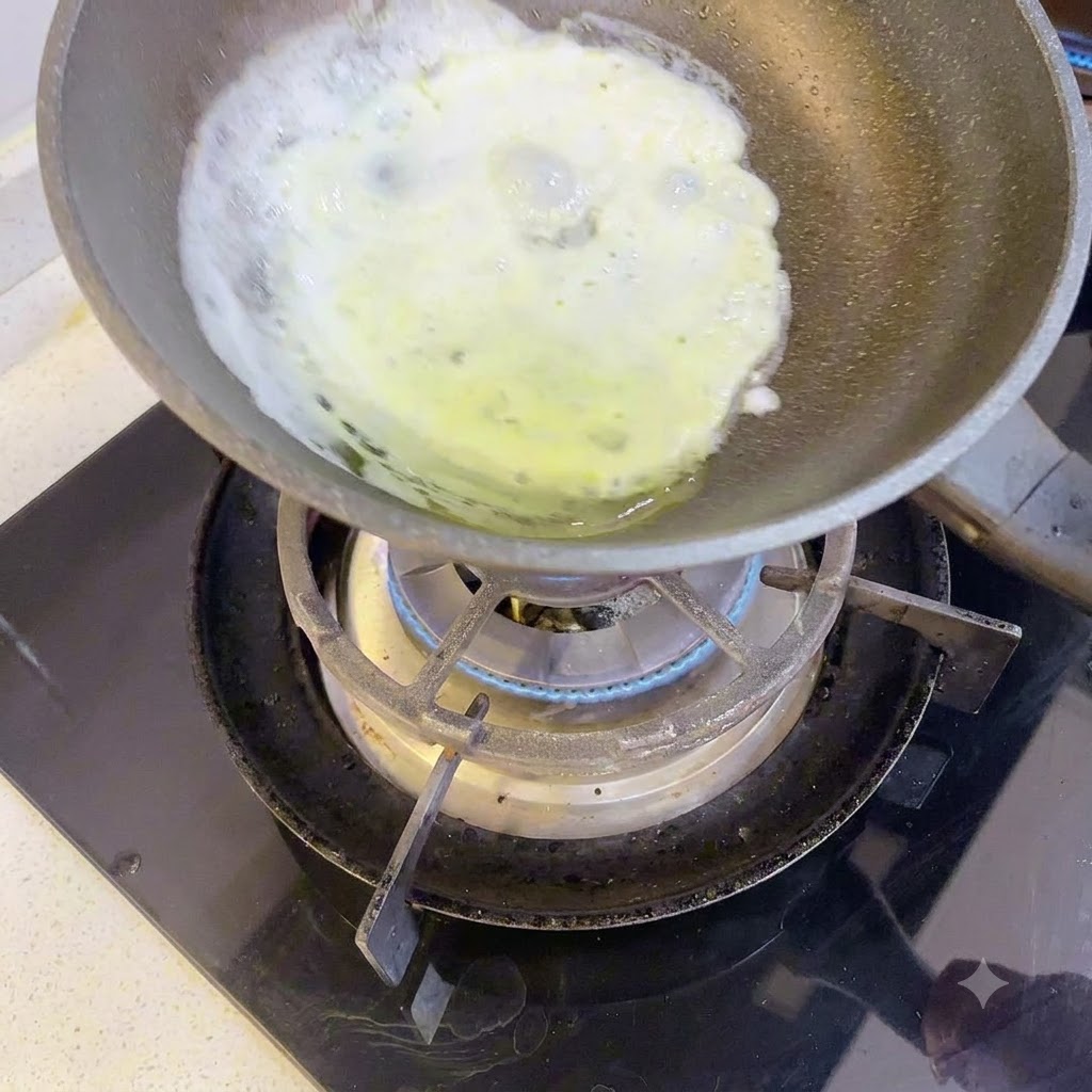 Un sottile strato di albume che cuoce in una piccola padella su un fornello a gas.