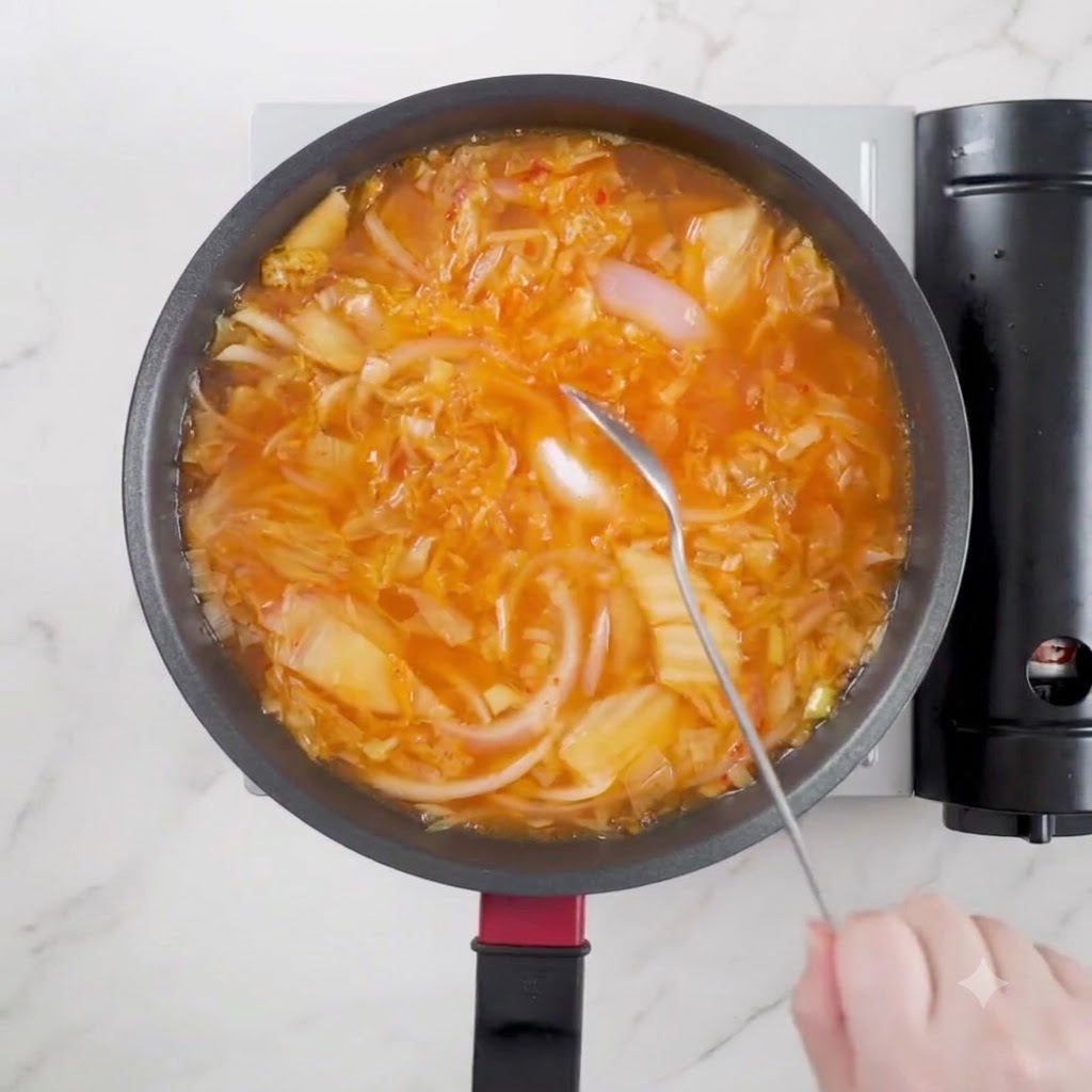 Un cucchiaio di salsa di soia chiara versato nella zuppa in cottura.