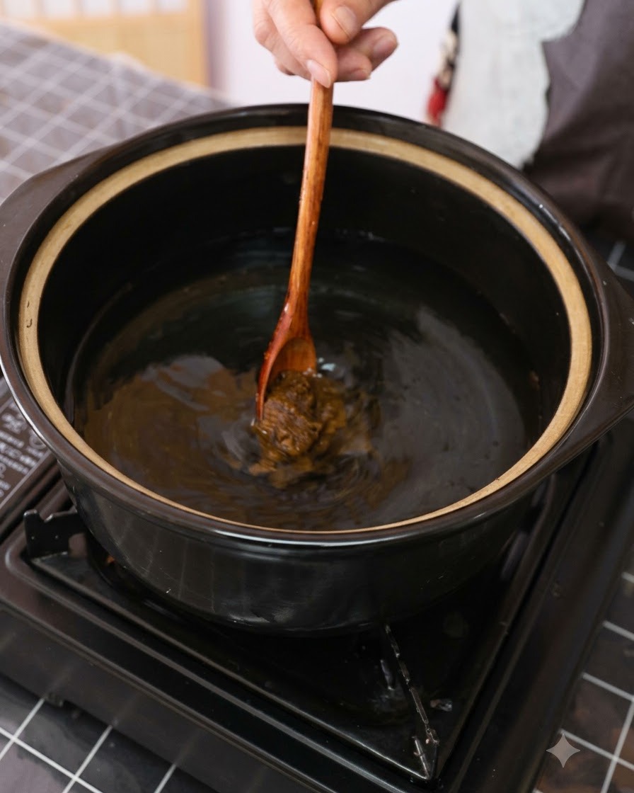 Pasta di soia marrone mescolata in una pentola dacqua con un cucchiaio di legno.
