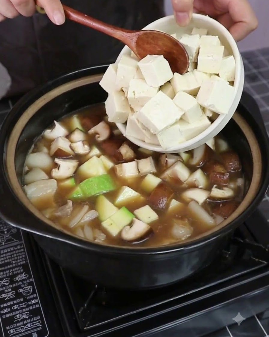 Cubetti di tofu sodo aggiunti nella pentola con verdure e brodo.