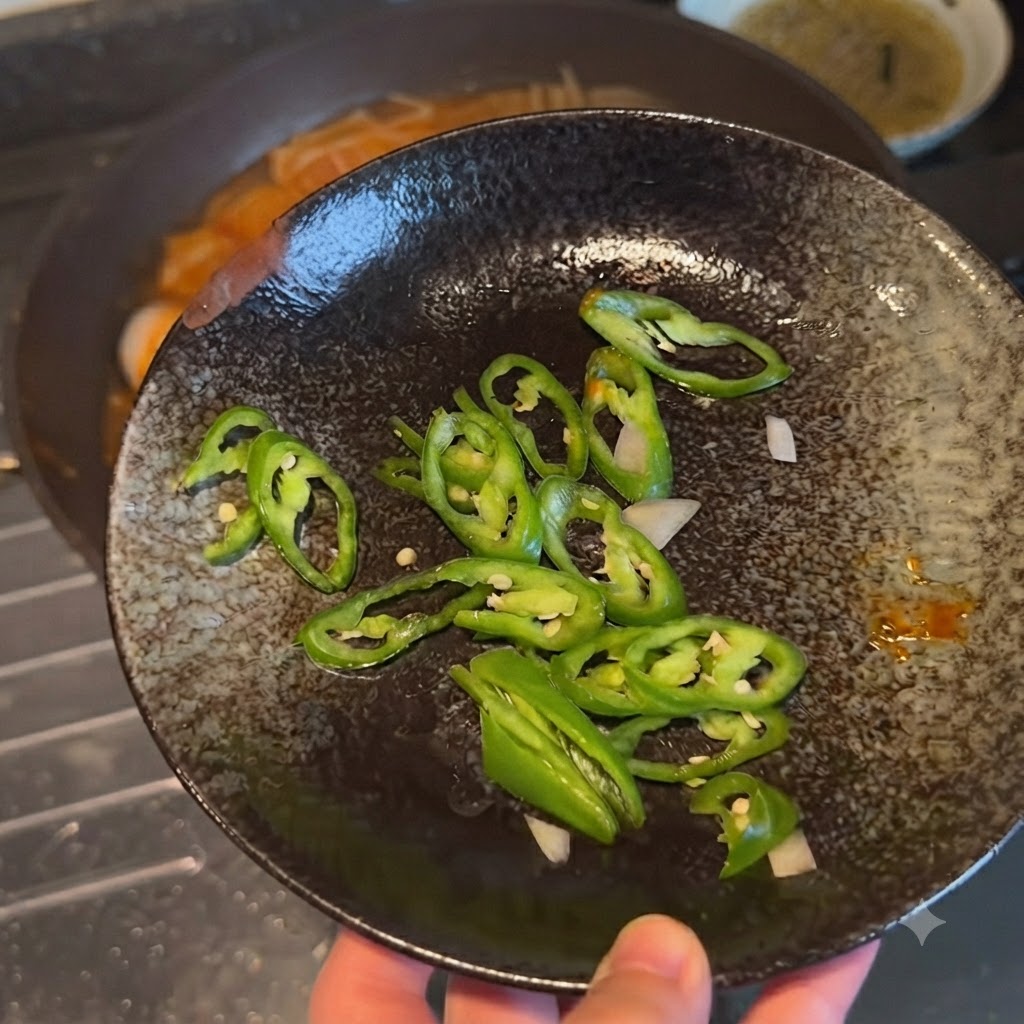 Peperoncini verdi affettati disposti su un piatto scuro decorativo prima di essere aggiunti al piatto.