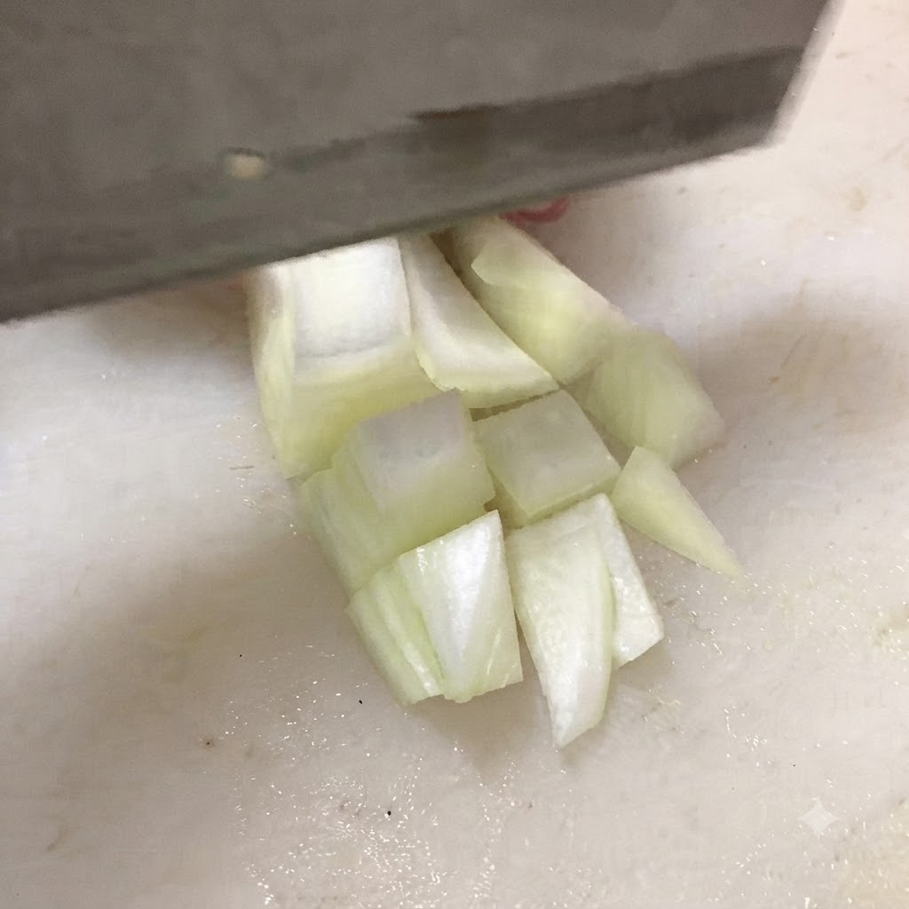 Un coltello che taglia il tofu fermo in cubetti spessi su un tagliere bianco.