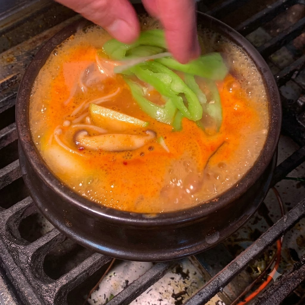 Fette di peperoncino verde fresco che cadono nello stufato di pasta di soia coreano rosso-arancio ribollente.