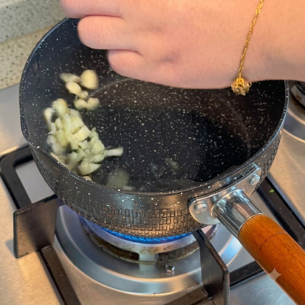 Aglio a fette che sfrigola nellolio caldo allinterno di una pentola su un fornello a gas.