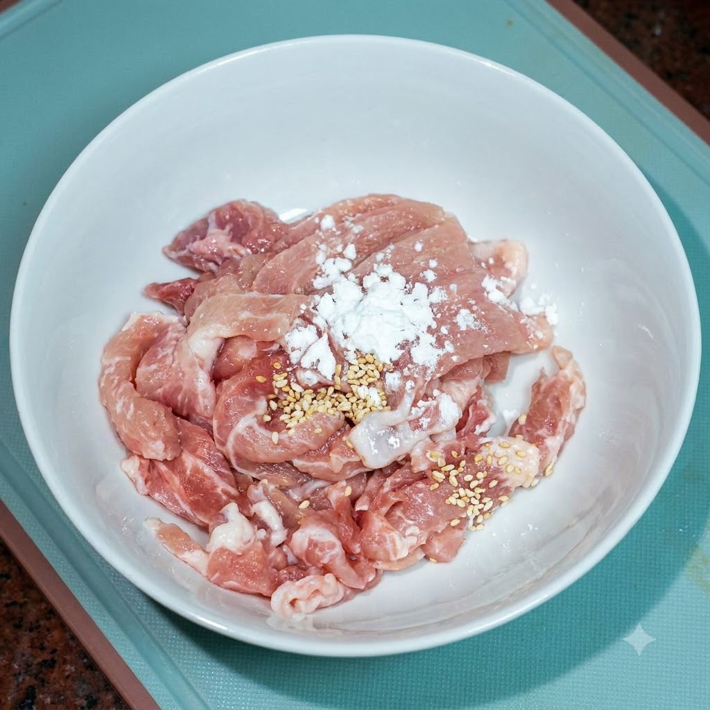 Fettine di maiale in una ciotola bianca condite con un po di brodo di pollo e olio.