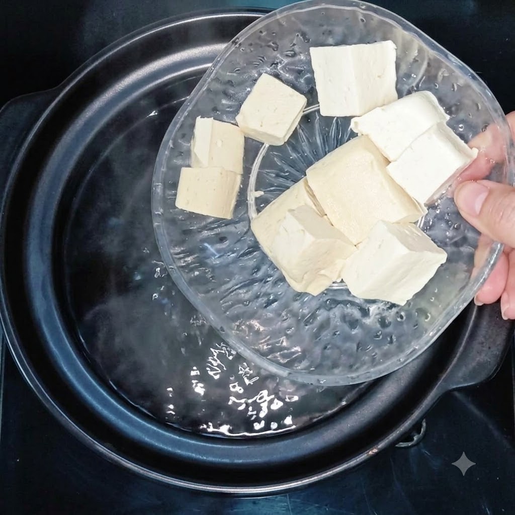 Cubetti di tofu aggiunti in una pentola di acqua bollente.