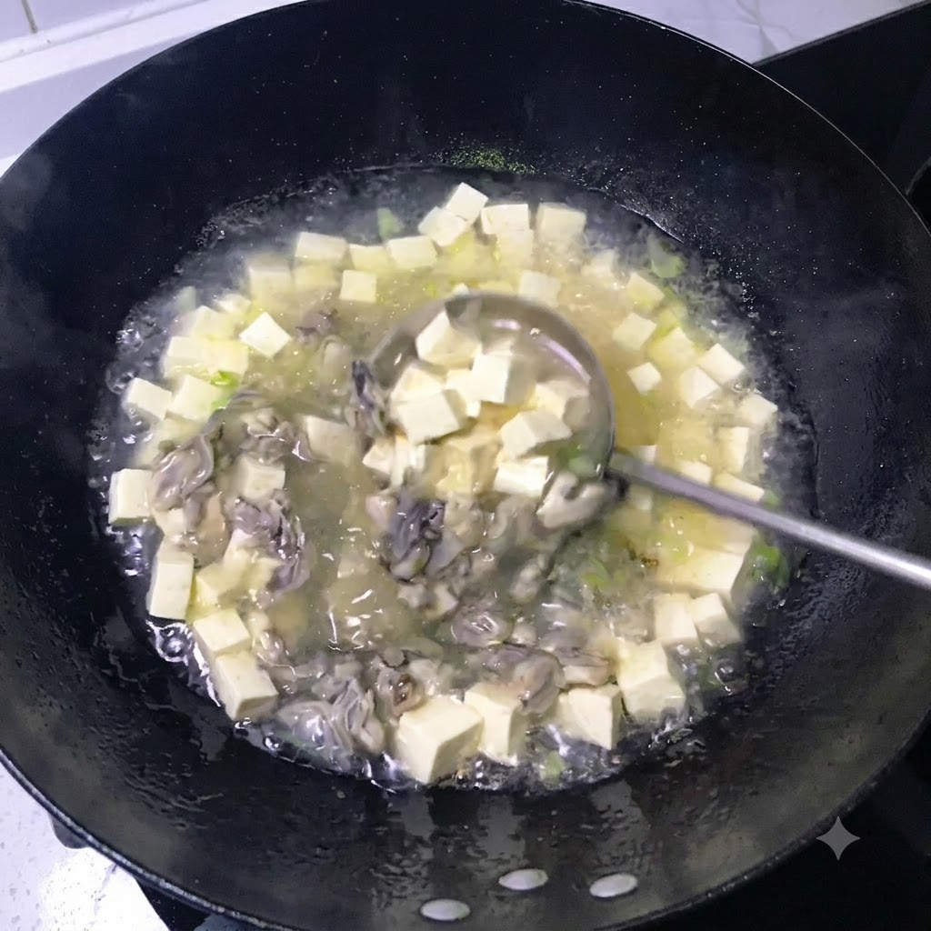 Un mestolo che mescola un brodo ricco e bianco latte pieno di tofu a dadini e ostriche cotte in un wok nero.