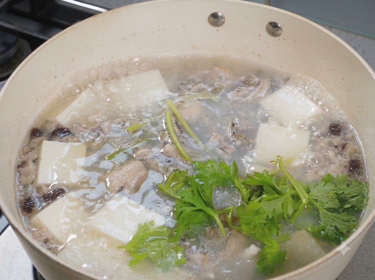 Foglie di sedano fresco sparse su una pentola ribollente di zuppa di ostriche e tofu.
