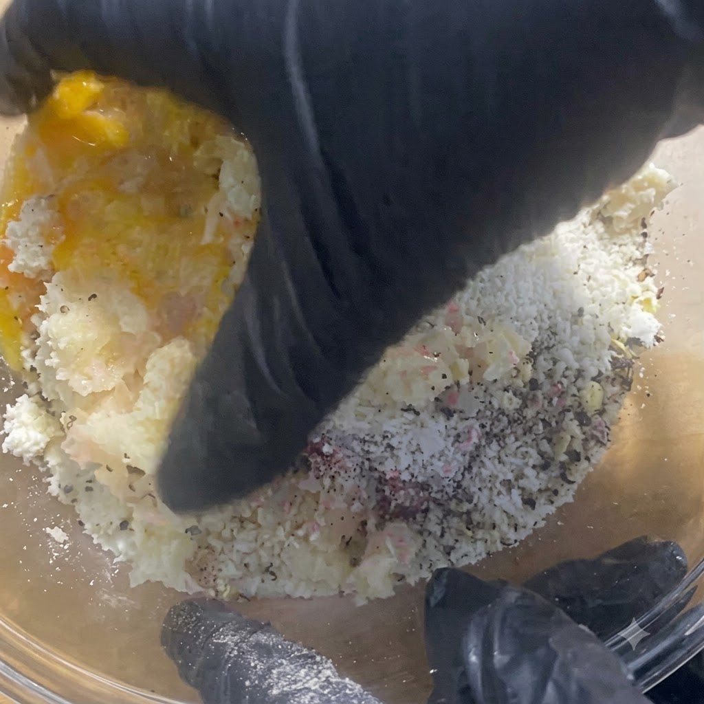 Mani guantate che mescolano e impastano accuratamente il ripieno di carne allinterno della ciotola di vetro.