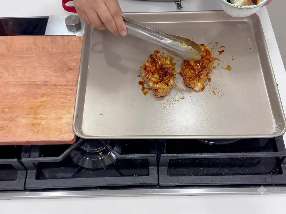 Cosce di pollo marinate che friggono con la pelle rivolta verso il basso in una padella quadrata riscaldata.