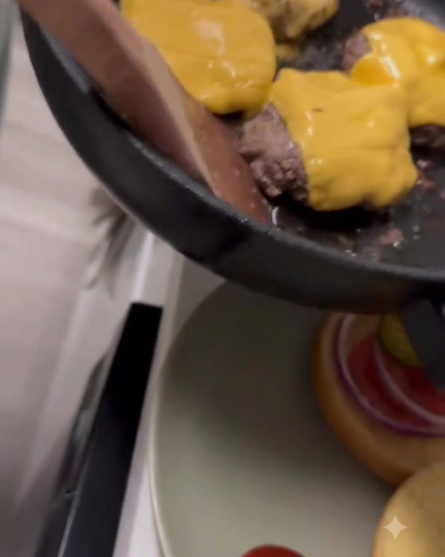 Formaggio cheddar giallo che si scioglie sopra i patty di manzo allinterno di una padella.