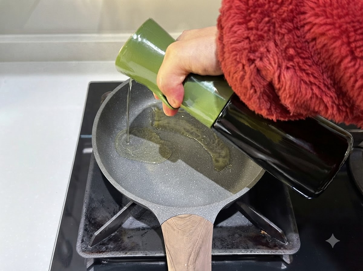 Olio doliva versato da un contenitore verde in una padella calda.