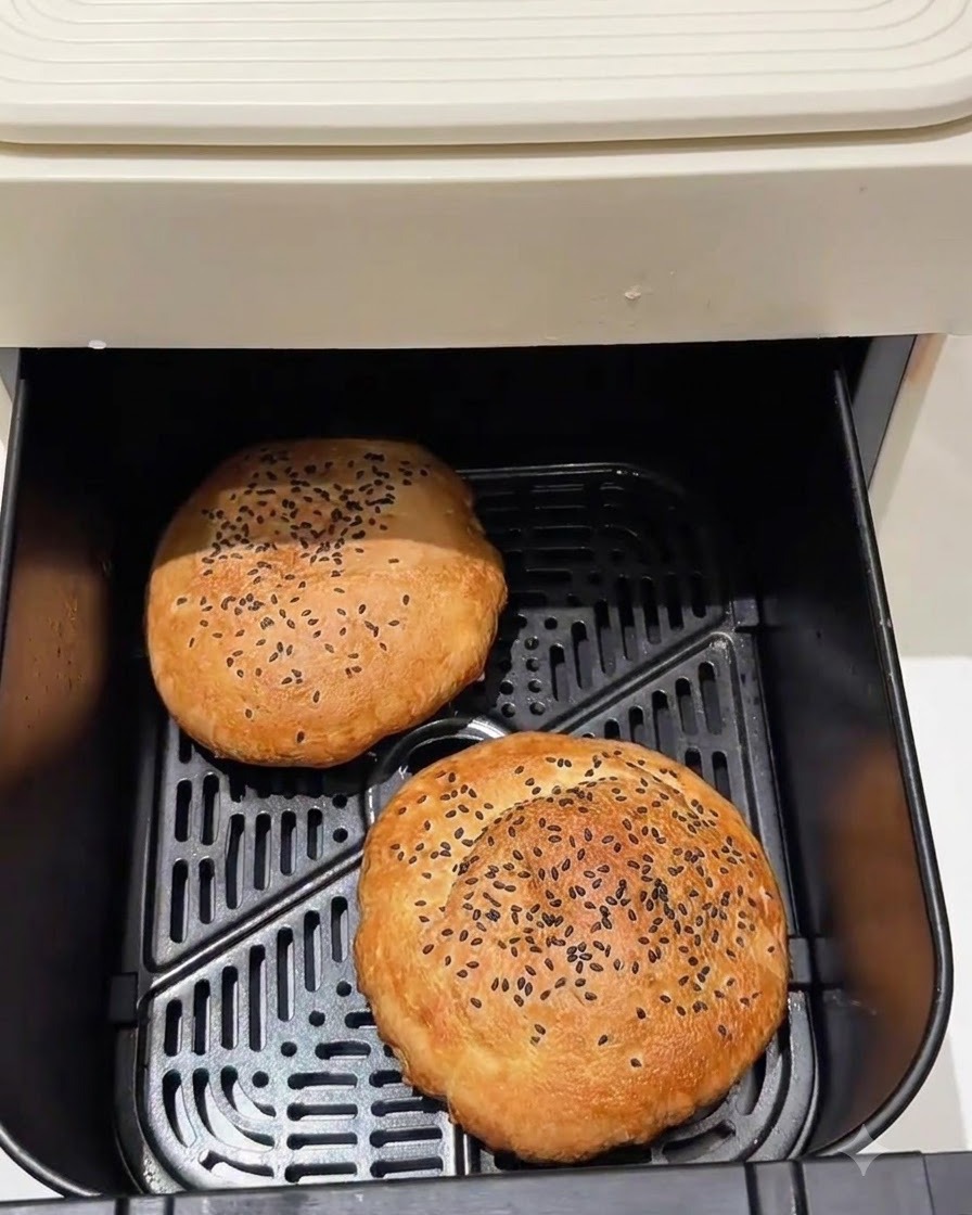 Panini per hamburger cotti allinterno di un cestello per friggitrice ad aria.