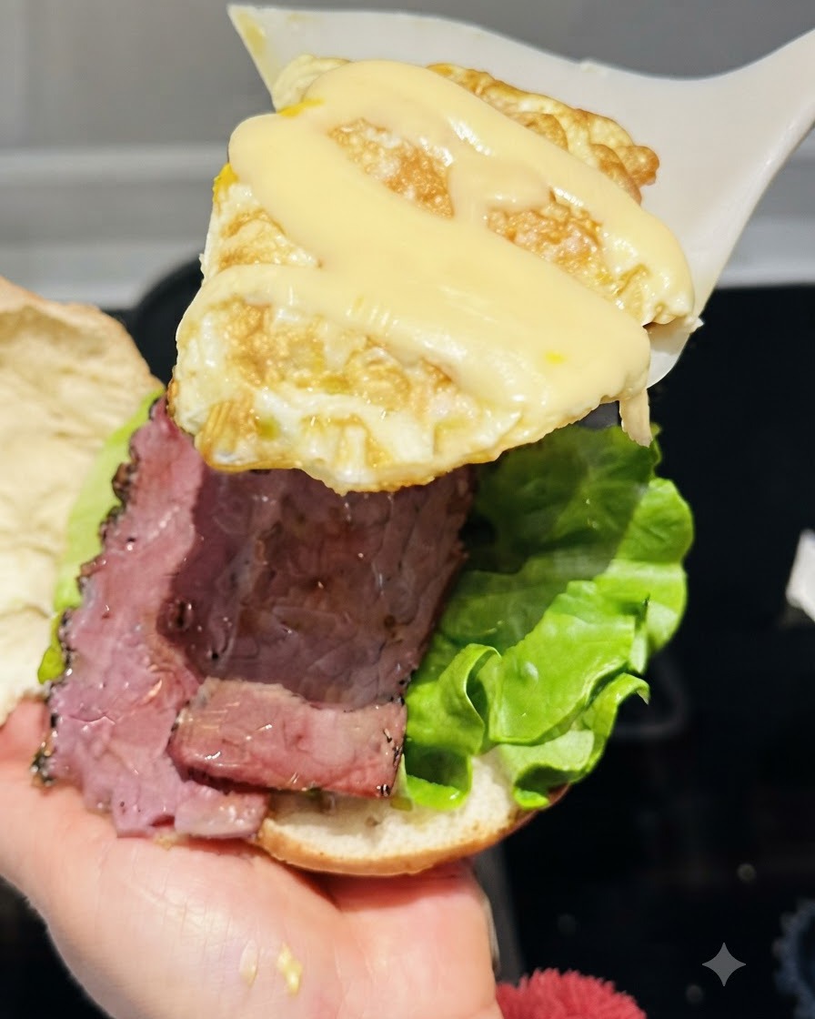 Una spatola che solleva un uovo fritto guarnito con formaggio filante fuso sopra la composizione dellhamburger.