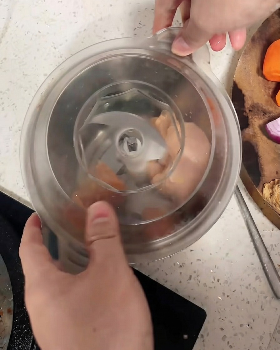 Un robot da cucina con il coperchio chiuso sopra i pezzi di pollo.