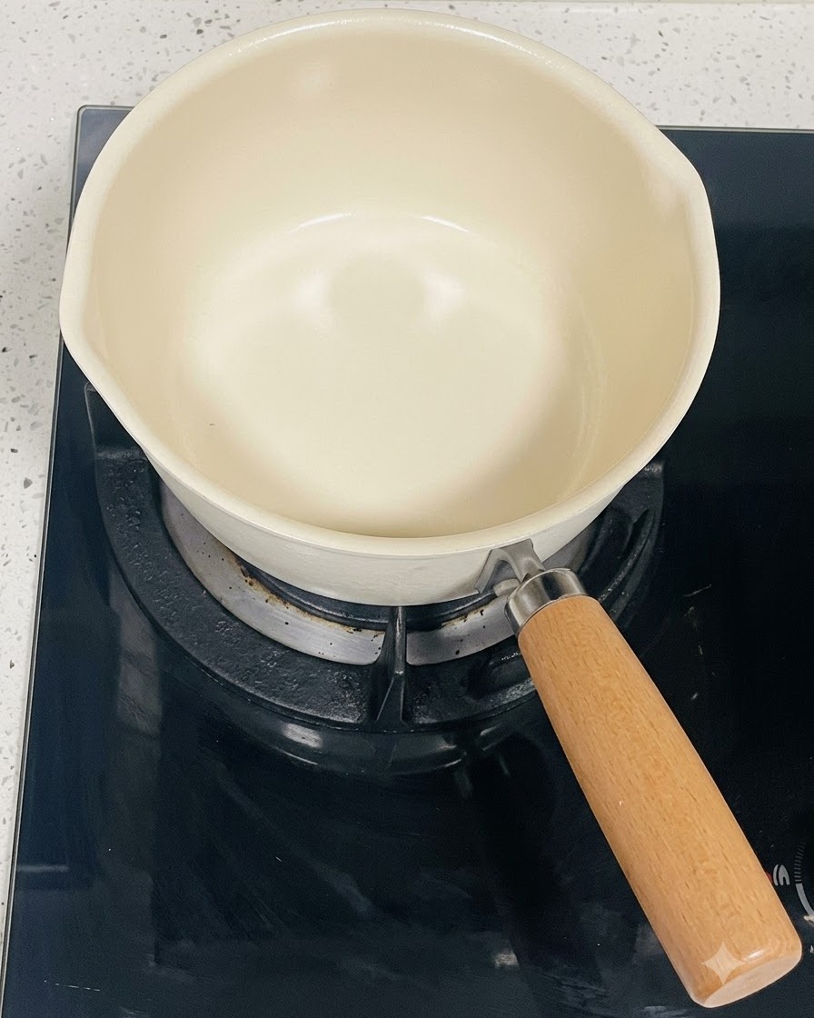 Una pentola pulita color crema posizionata su un piano cottura a induzione nero.