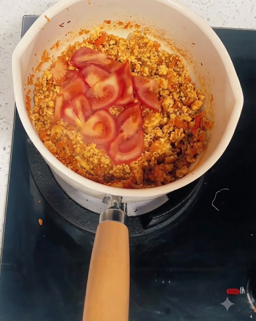 Fette di pomodoro sul composto cotto in una pentola in cui vengono aggiunti acqua e concentrato di pomodoro.