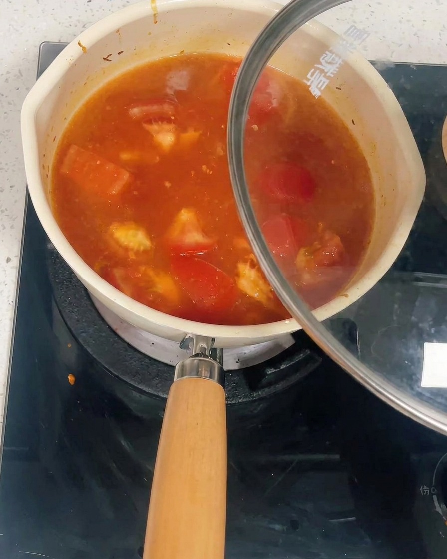 Una pentola piena di salsa di pomodoro e pollo coperta con un coperchio di vetro.