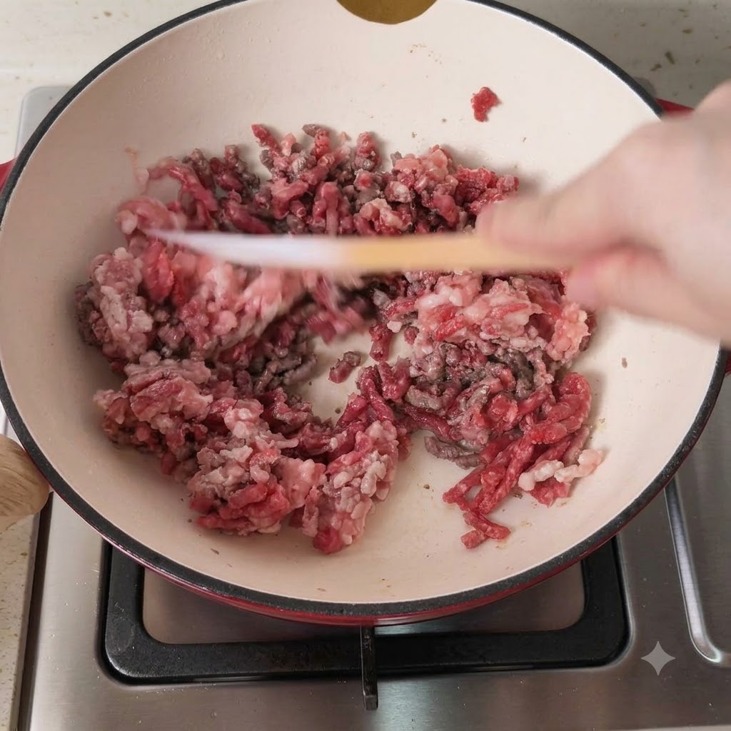 Carne macinata mista di maiale e manzo in fase di rosolatura in una pentola calda.