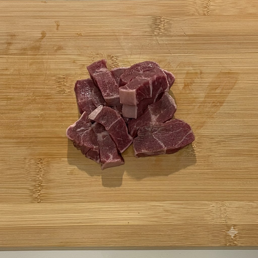 Pezzi di carne di manzo cruda caricati nella ciotola dacciaio di un robot da cucina.