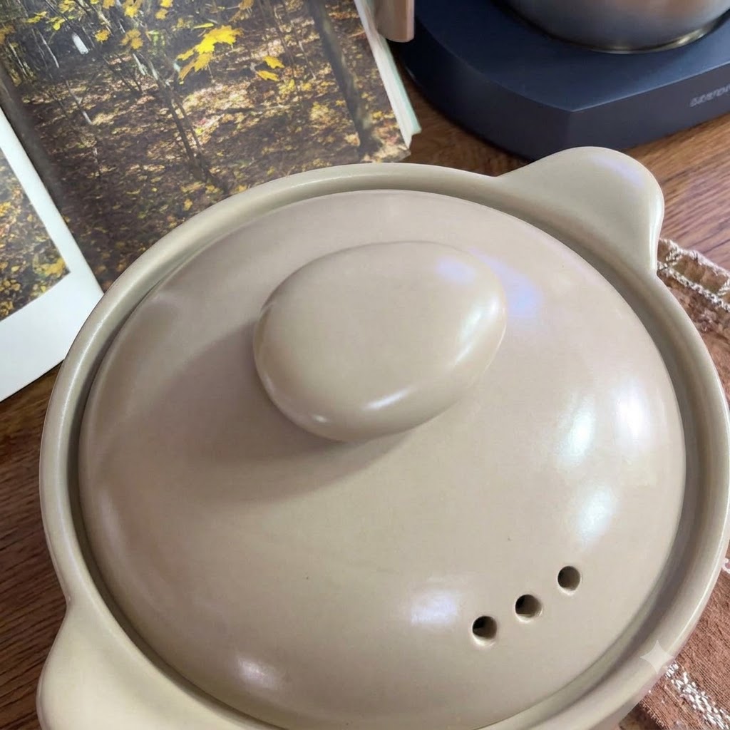 Pomodori freschi disposti su una teglia accanto a una pentola di ceramica.