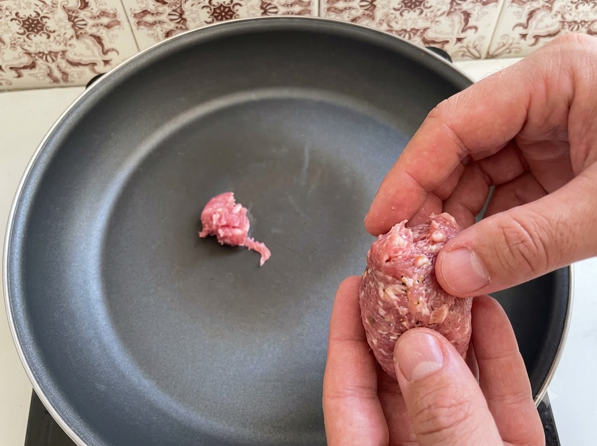 Pezzi di carne di salsiccia italiana disposti e messi in una padella.