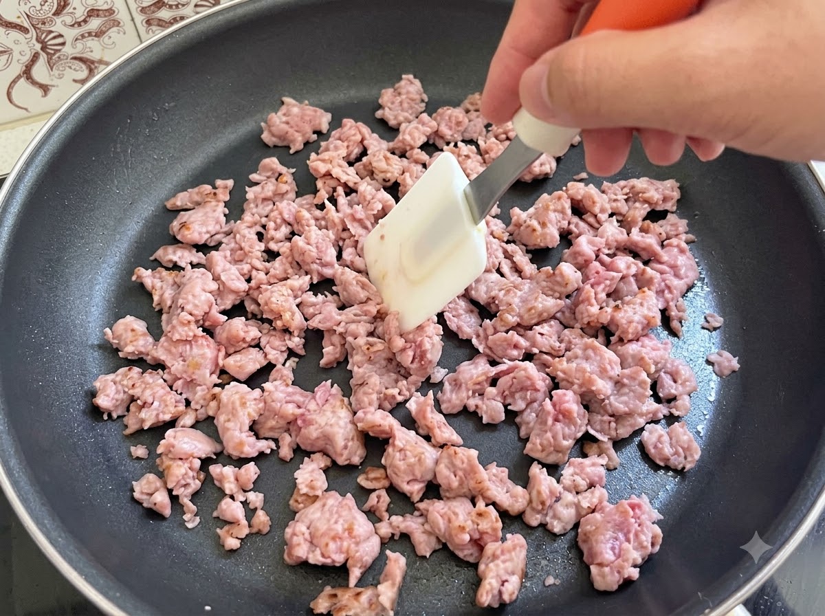 Carne di salsiccia italiana mescolata attivamente e fritta con una spatola in una padella.