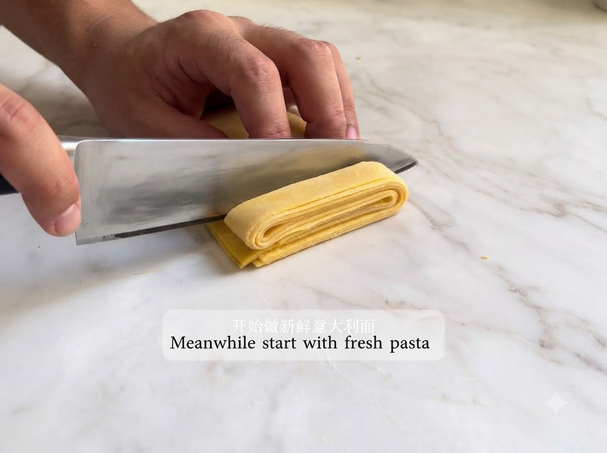 Sfoglia di pasta stesa piegata e tagliata a strisce con un coltello.