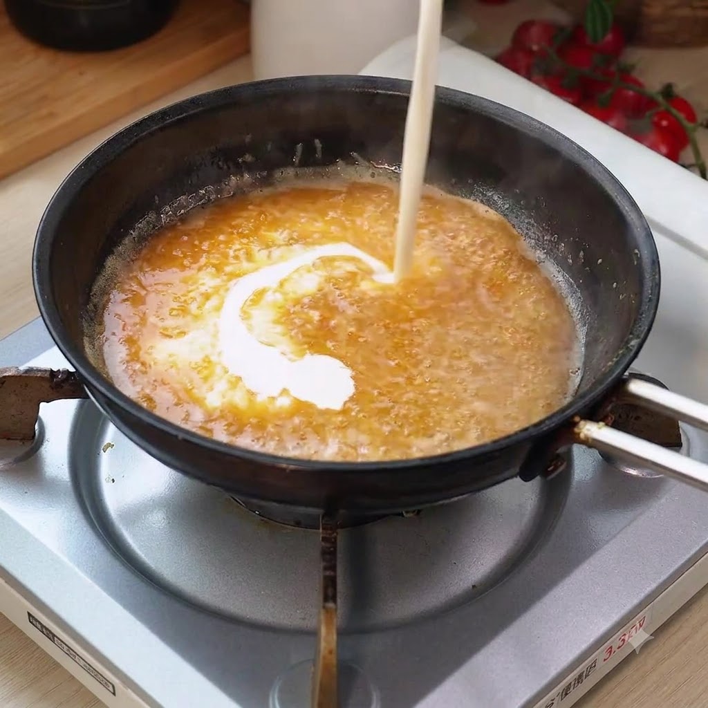 Panna da cucina versata nella salsa bollente in padella, creando un vortice cremoso.